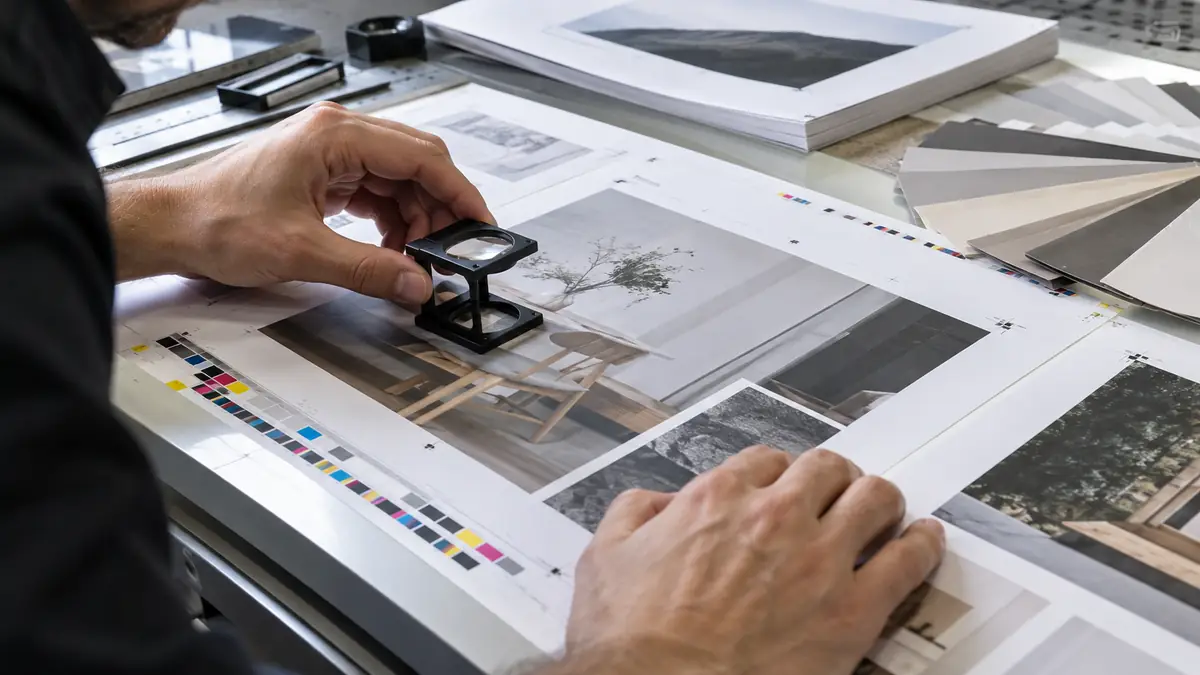 Primer plano de revisión de pruebas de impresión con cuentahílos y barras de control CMYK